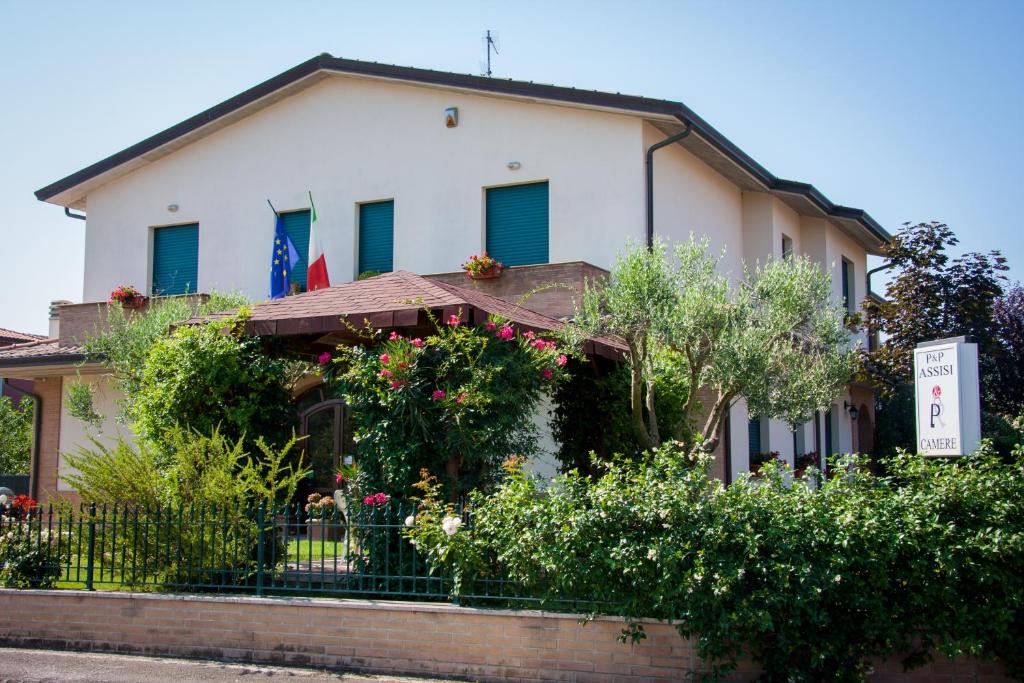 a white house with blue shuttered windows and plants at P&P Assisi Camere in Bastia Umbra