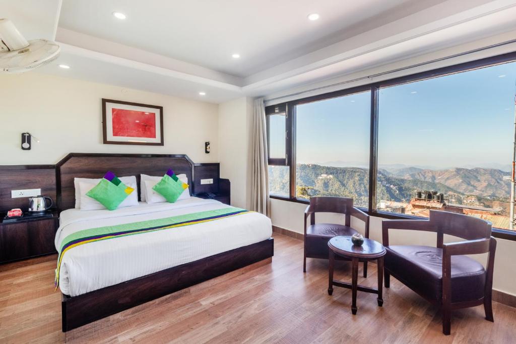1 dormitorio con 1 cama, mesa y sillas en Treebo Trend Maharaja 500 Mtrs From Mall Road, en Shimla