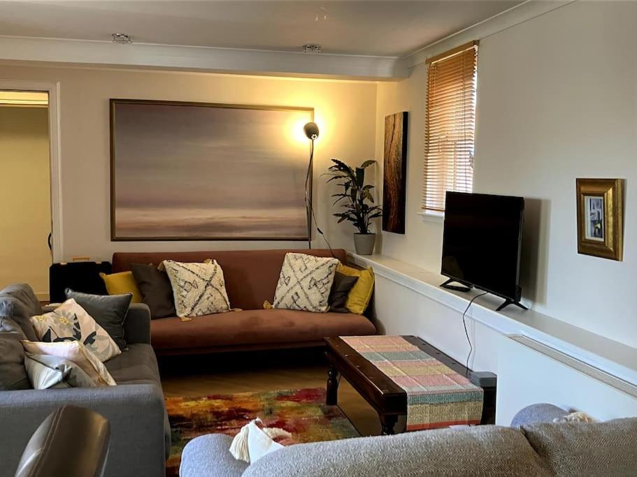a living room with a couch and a flat screen tv at Bright central large cosy flat in Fife