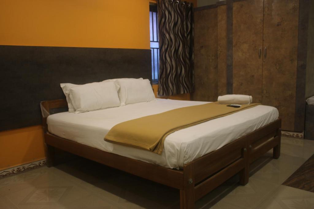 a bedroom with a bed with white sheets and a window at Hotel Sikara, Kumbakonam in Kumbakonam