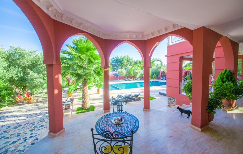 różowy dom ze stołem i basenem w obiekcie Ferme Prestige w mieście Moulay Yacoub