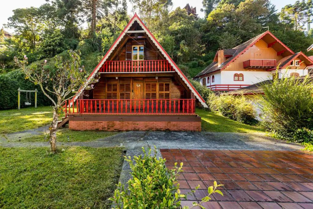 a house with a red roof and a yard at Chalé inteiro completo a 5 min a pé do Capivari - Campos do Jordão in Campos do Jordão