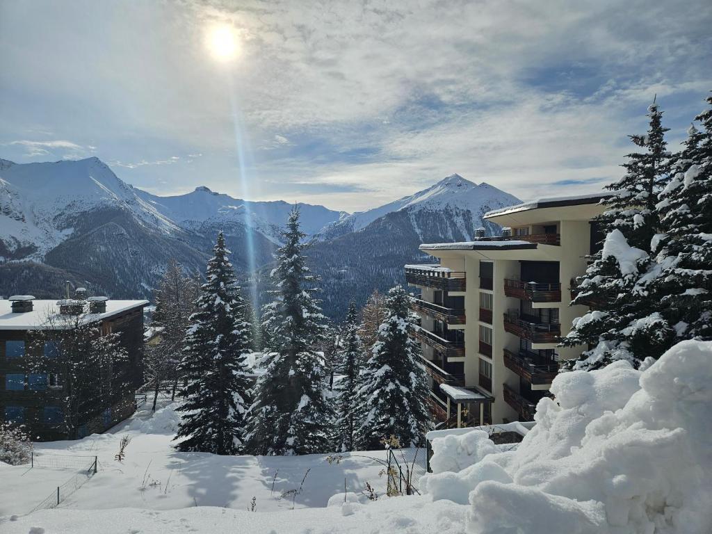 une montagne enneigée avec un bâtiment et des arbres dans l'établissement Studio Cosy Plein Soleil, à Orcières