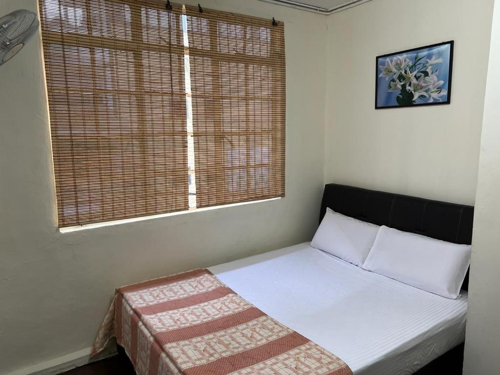 ein kleines Bett in einem Zimmer mit Fenster in der Unterkunft De Cameron Guest House in Tanah Rata