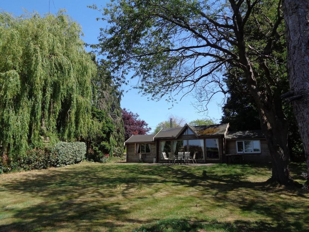 een huis in een tuin met een boom bij Idyllic Log Cabin Near Stratford upon Avon in Stratford-upon-Avon