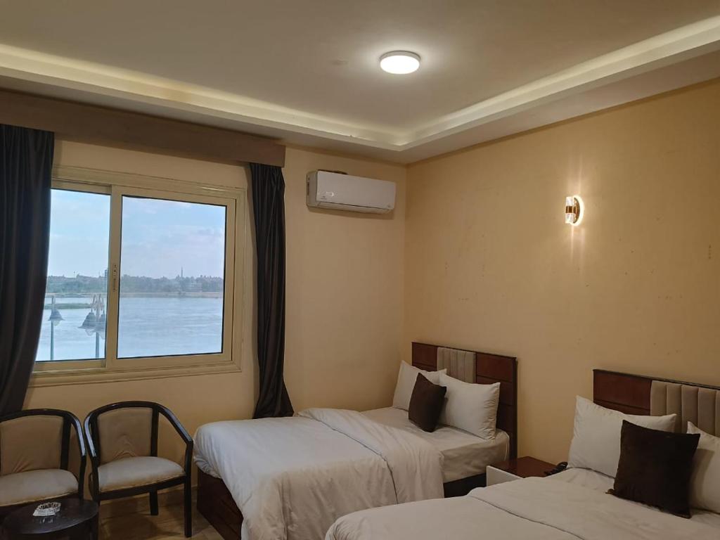 Habitación de hotel con 2 camas y ventana en Nile jewel hotel beni suef, en Beni Suef