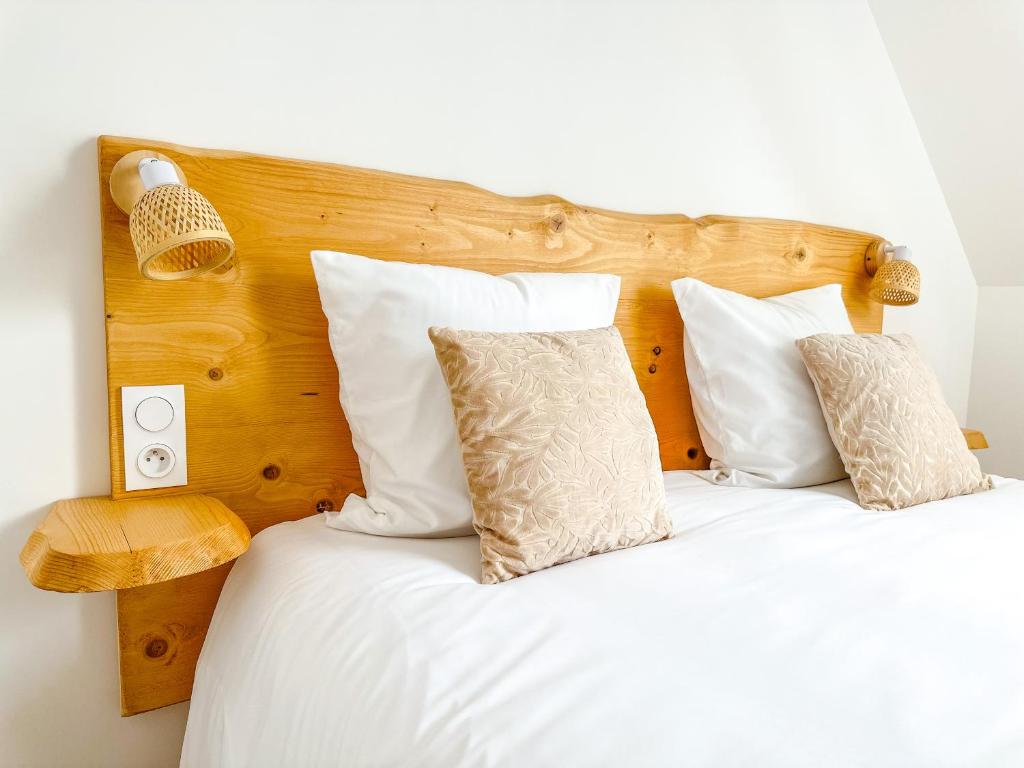 um quarto com uma cama com lençóis brancos e almofadas em Le cocon de Normandy em Criquebeuf-sur-Seine