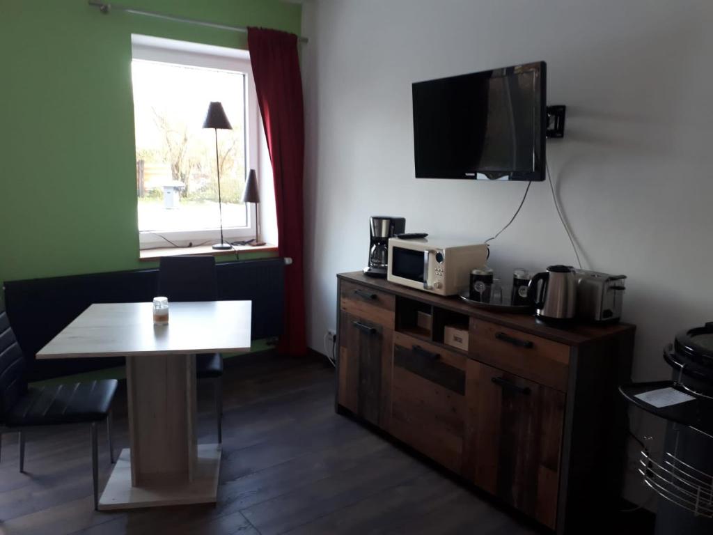 a room with a table and a tv on the wall at Ferienwohnung am Schwimmteich in Lachendorf