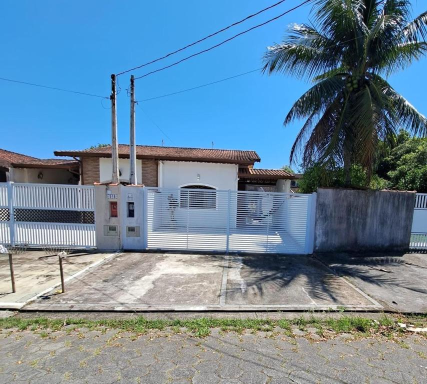 una recinzione bianca di fronte a una casa con una palma di CASA DE PRAIA MARAVILHOSA PERUIBE a Peruíbe