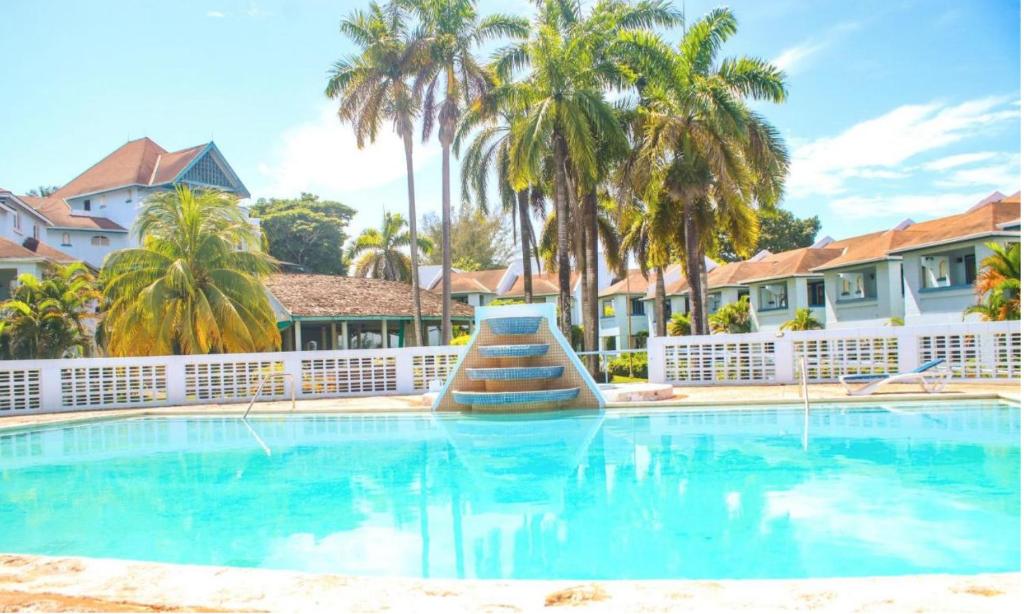 einen Pool in einem Resort mit Palmen in der Unterkunft STUNNING 2 Bedroom House at Point Village Negril in Negril