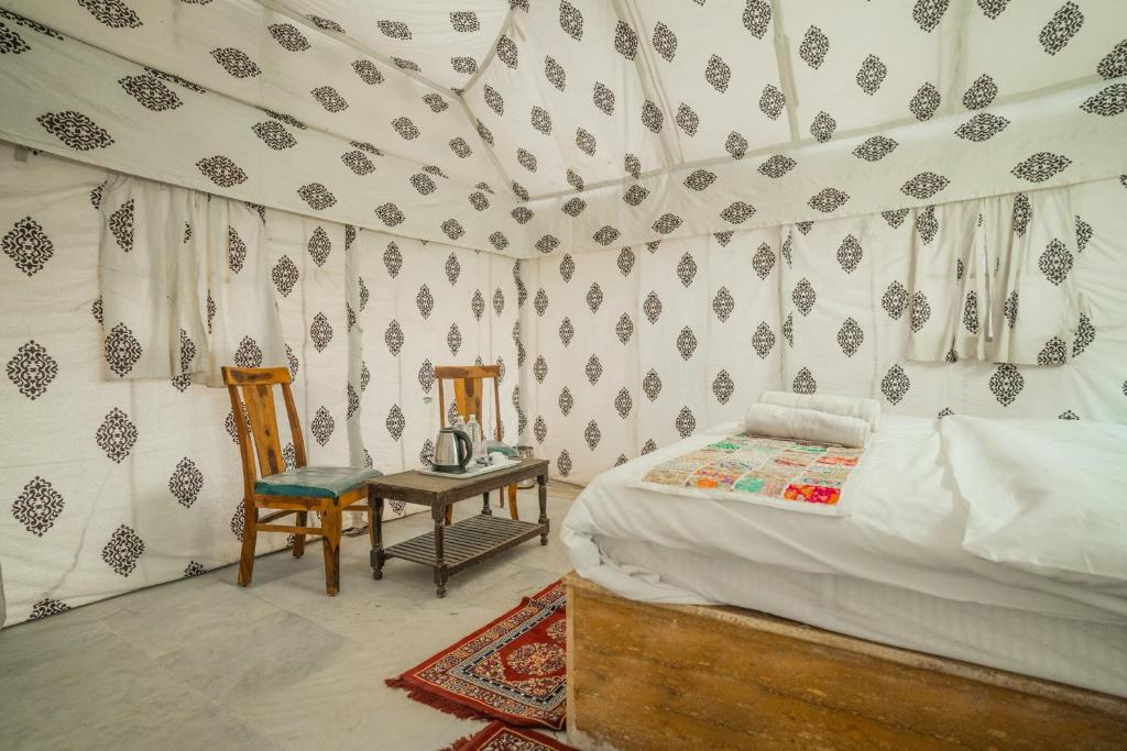 a bedroom with a bed and a table and a chair at Dynasty Desert Camp and Resort in Sām