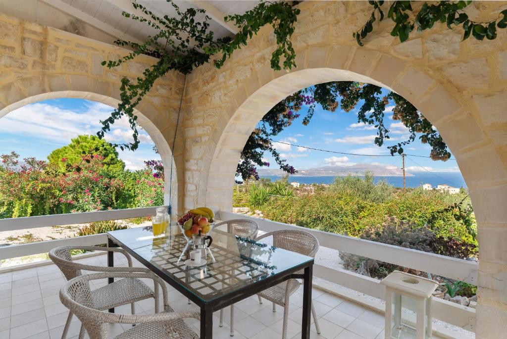 a dining room with a table and two arched windows at Villa Calliope St George Retreat BY APOKORONAS-VILLAS in Kókkinon Khoríon
