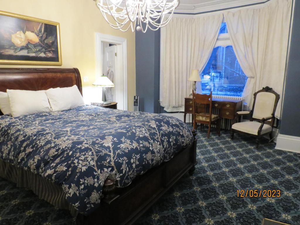 een slaapkamer met een bed, een bureau en een stoel bij The Roses Heritage Inn in St. John's