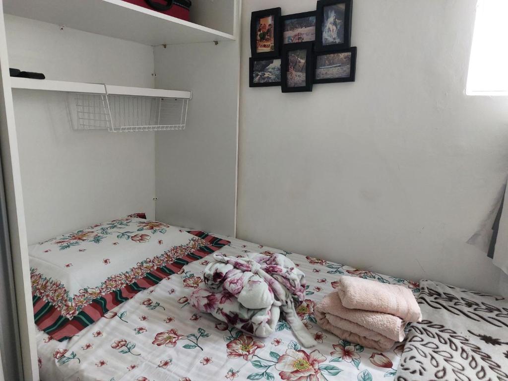 a bedroom with a bed with a floral quilt on it at PEQUENO QUARTO individual-PERTO DO CENTRO DE CONVENÇÕES-FENEARTE - RECIFE - ventilador,TV,mesa de trabalho in Recife