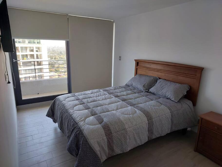 een slaapkamer met een bed en een groot raam bij Apartamento Nuevo Mall y metro Plaza Egaña in Santiago