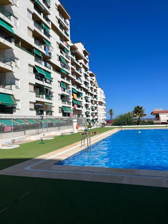 uma piscina em frente a um grande edifício de apartamentos em APARTAMENTO NUEVO CÉNTRICO en PRIMERA Línea de playa con vistas al Mar, Piscina, aire acondicionado y wifi em Peníscola