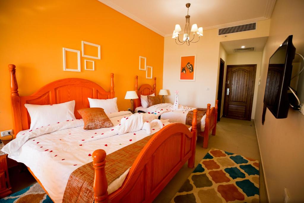 two beds in a bedroom with orange walls at Holy Family Hotel in Jabal aţ Ţayr