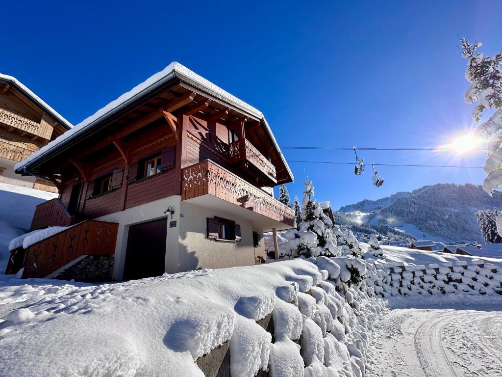 a house covered in snow next to a fence at Le Chalet des Ours in Châtel