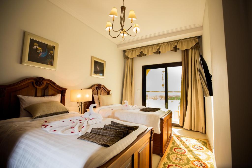 a bedroom with two beds and a chandelier at Holy Family Hotel in Jabal aţ Ţayr