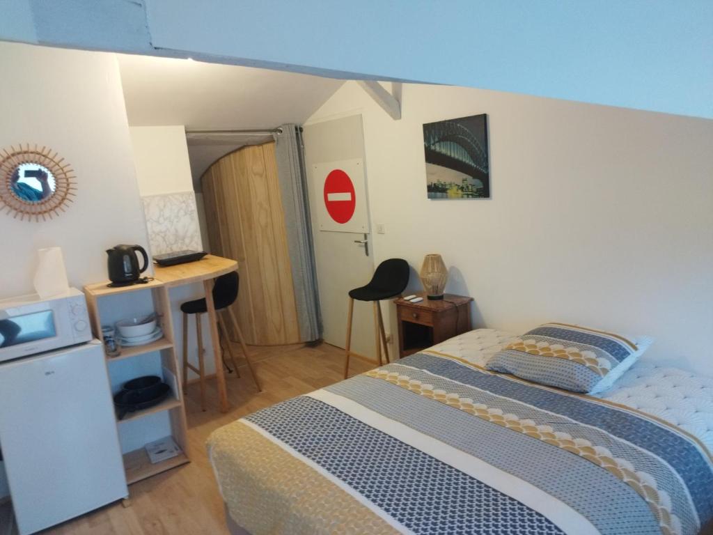 Un dormitorio con una cama y un escritorio en una habitación. en Studio au coeur de la ferme, en Saint-Lumine-de-Coutais