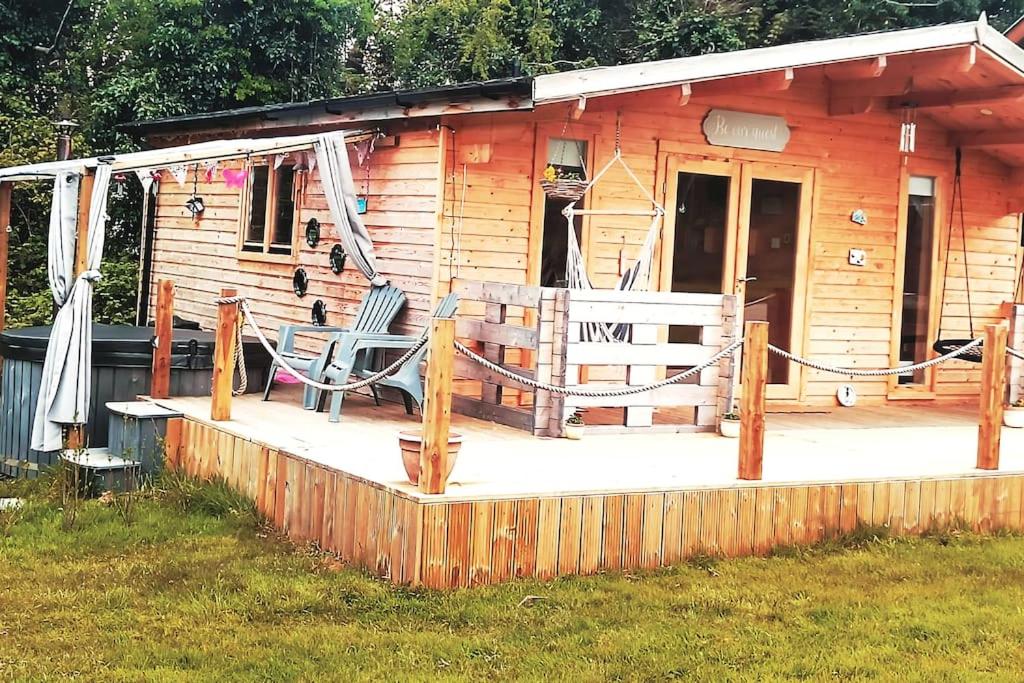 una casa con un porche con una silla en Luxury log cabin with wood fired hot tub en Moville