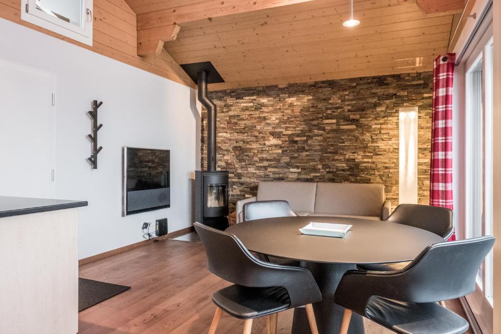 d'une salle à manger avec une table, des chaises et un mur en briques. dans l'établissement Chalet Eiger View - GRIWA RENT, à Grindelwald