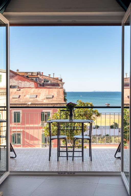a table and chairs on a balcony with a view of the ocean at Pangea Rooms in Castellammare di Stabia