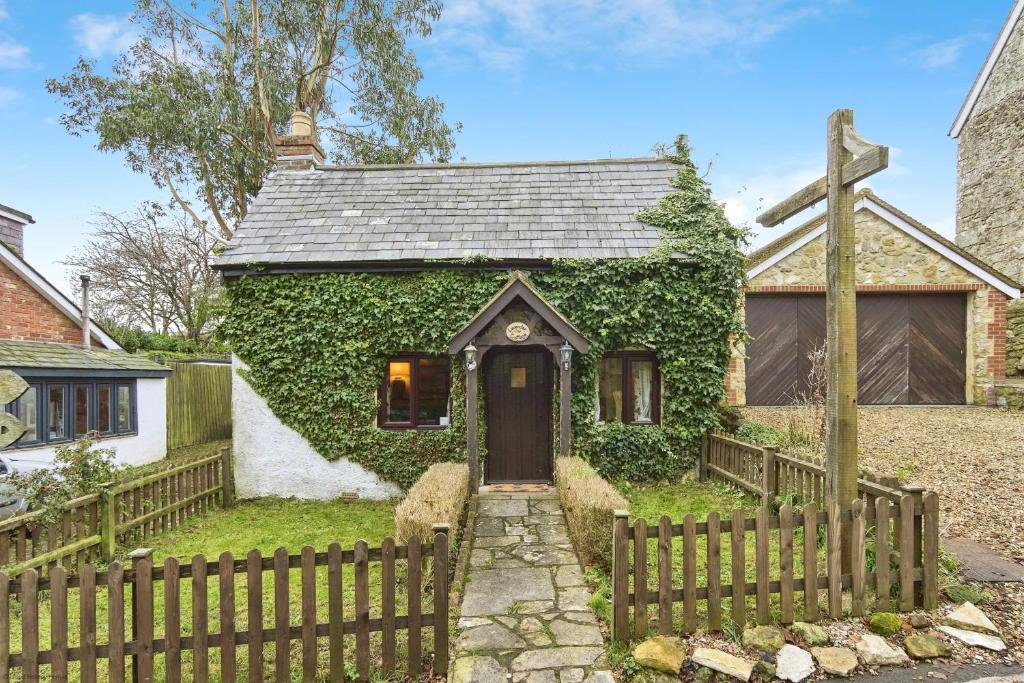 a house covered in ivy with a wooden fence at Lavender Cottage in Arreton
