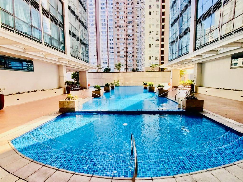 a large blue pool in a building with tall buildings at Deluxe Queen 1BR Luxury Suite 17 - Pool, City View in Manila