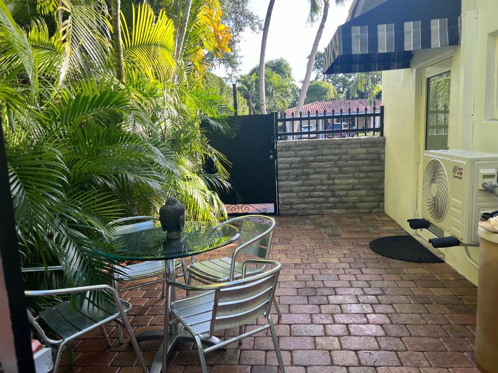 a patio with a table and chairs and palm trees at VILLA GUILLA in Miami