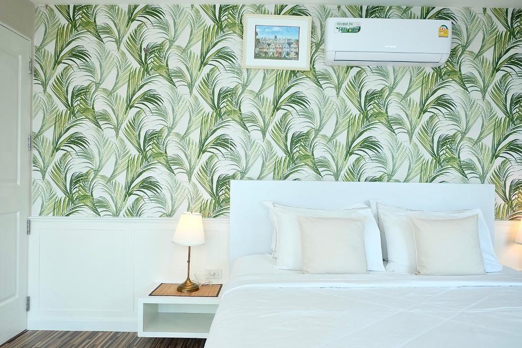 a bedroom with a white bed with a green and white wallpaper at The Beach Bangsaen by Thanthita next to Wonnapa beach in Bangsaen