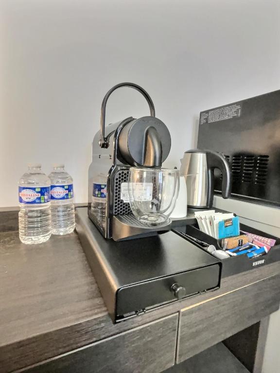 a kitchen counter with a coffee maker and water bottles at &#39;&#39;Les Platanes&#39;&#39;de Miss.K Conciergerie in Gorrevod