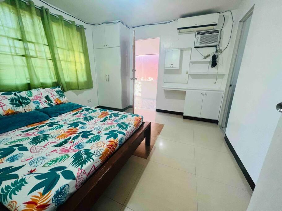 a bedroom with a bed with a floral bedspread and a kitchen at tranisient house @camella villa kanangga butuan city in Butuan