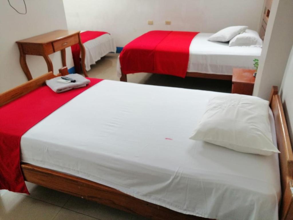 duas camas com lençóis vermelhos e brancos num quarto em Descanso del Petrel em Puerto Ayora