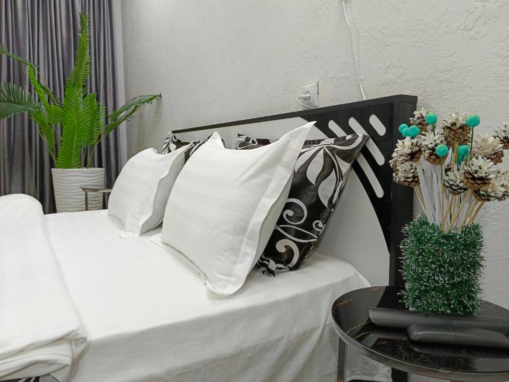 1 cama con almohadas blancas y negras y mesa en Островок Уюта, en Aktobe