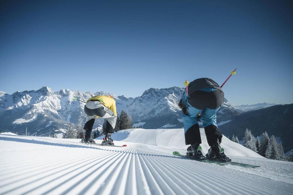 two people are skiing down a snow covered mountain at Central Hideaway in Maria Alm am Steinernen Meer