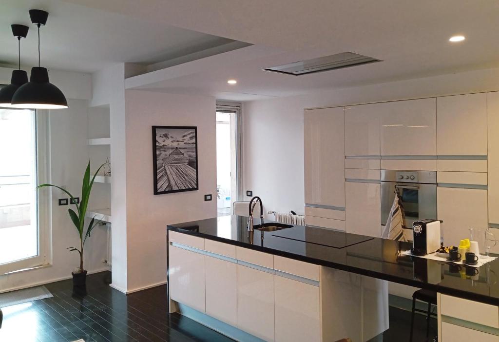 uma cozinha com armários brancos e um balcão preto em FrenzHouse - Terraced Apartment close to Rho Fiera and San Siro em Baranzate
