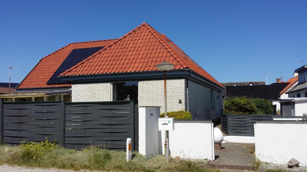 Nørre VorupørにあるBed & Breakfast i Vorupørのオレンジ色の屋根と黒い柵の家
