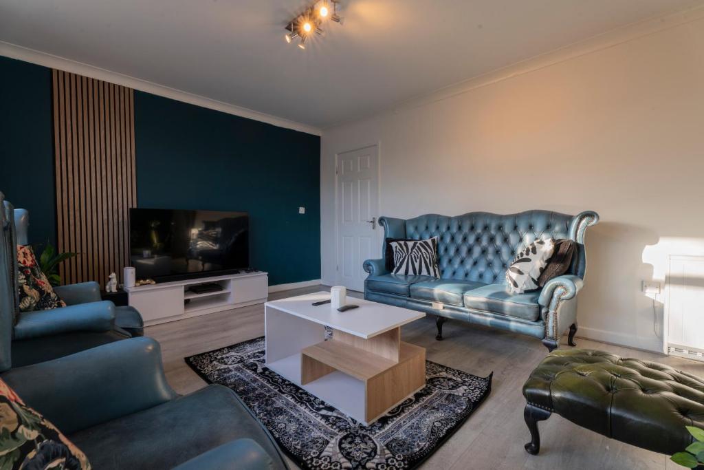 a living room with a blue couch and a tv at Abdon house in Birmingham