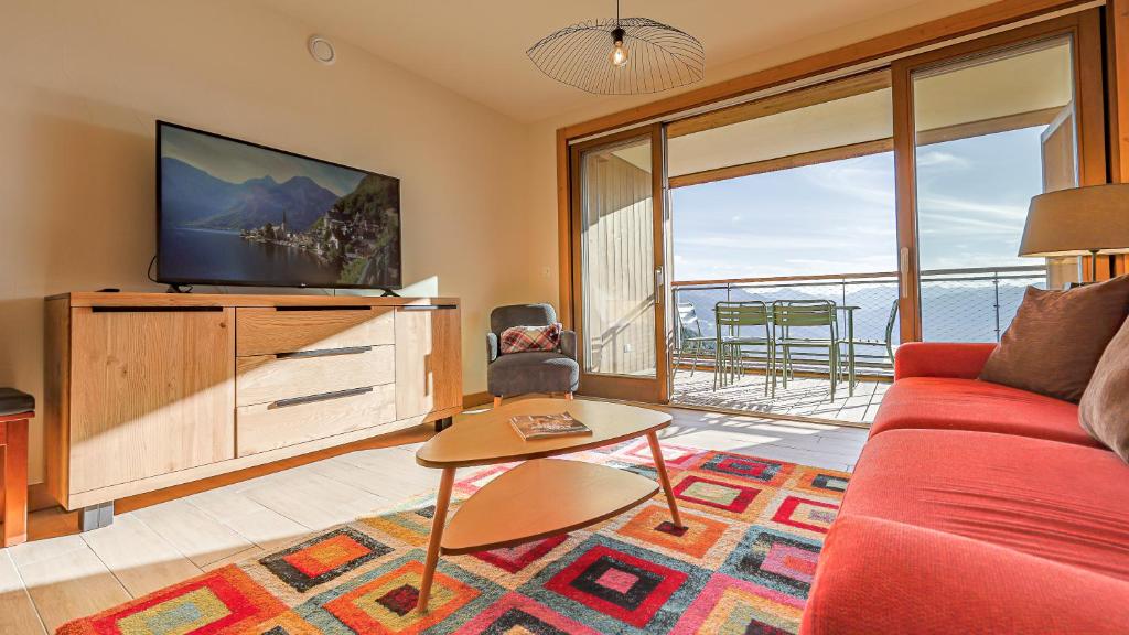 un salon avec un canapé rouge et une télévision dans l'établissement Arc 1600 SunsetPanorama Skis aux pieds 6 pers, à Bourg-Saint-Maurice