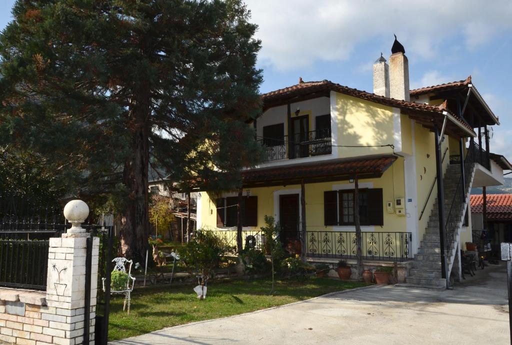 Una casa amarilla con un árbol delante. en Σοφίτα en Graviá