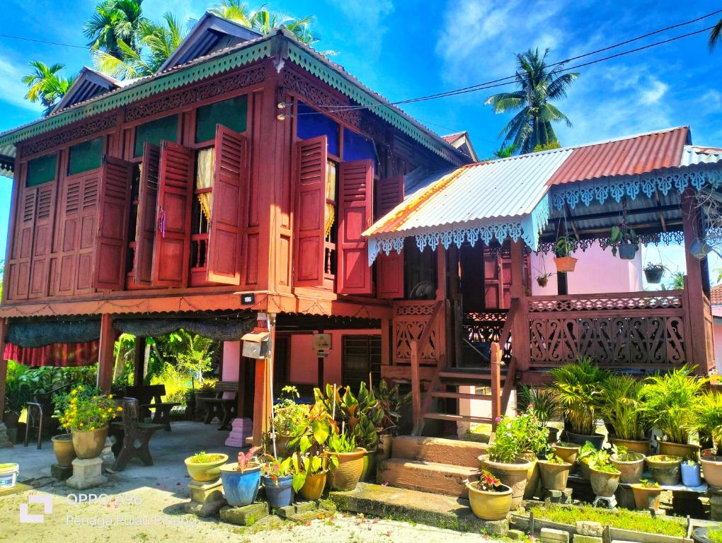 une maison colorée avec des plantes en pot devant elle dans l'établissement Homestay Teratak Kayu kota Aur, à Kepala Batas