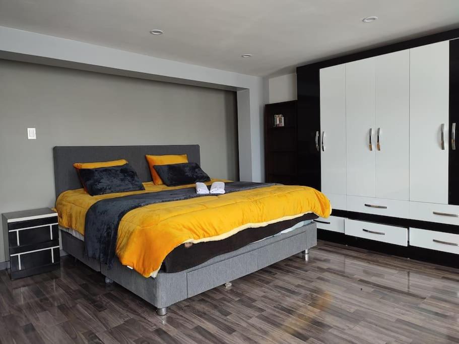 una camera da letto con un grande letto con lenzuola gialle di departamento independiente a Puno