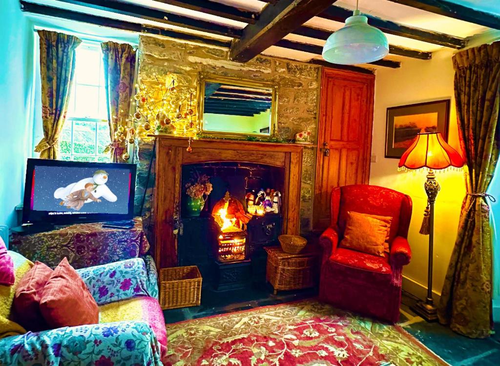 a living room with a fireplace and a bed and a chair at Castle Buildings Cottage1 in Llanrhaeadr-ym-Mochnant