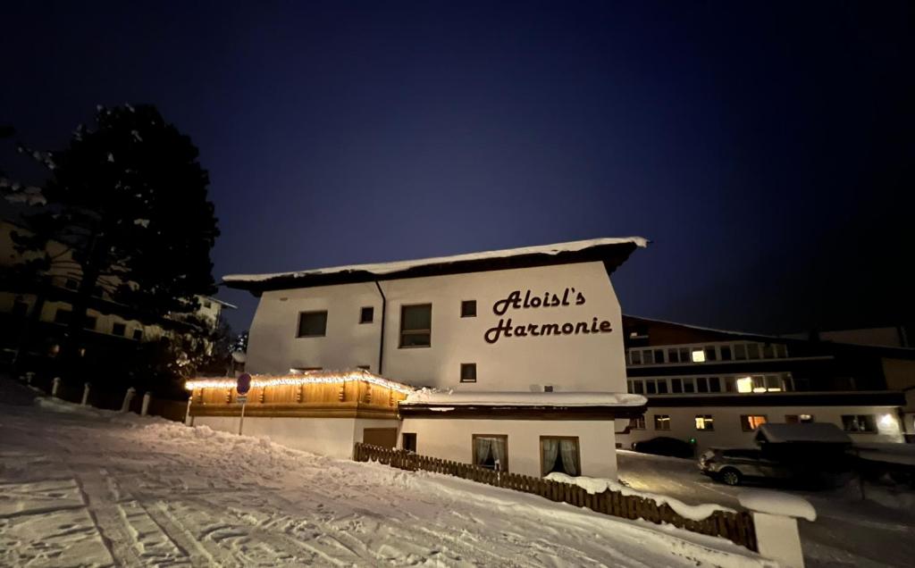 a building with a sign on it in the snow at Pension Aloisl`s Harmonie in Nauders