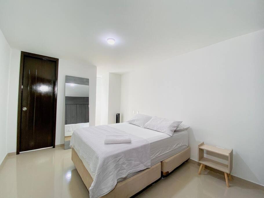 a white bedroom with a bed and a window at Excepcional Apartamento -WAIWA HOST in Bucaramanga