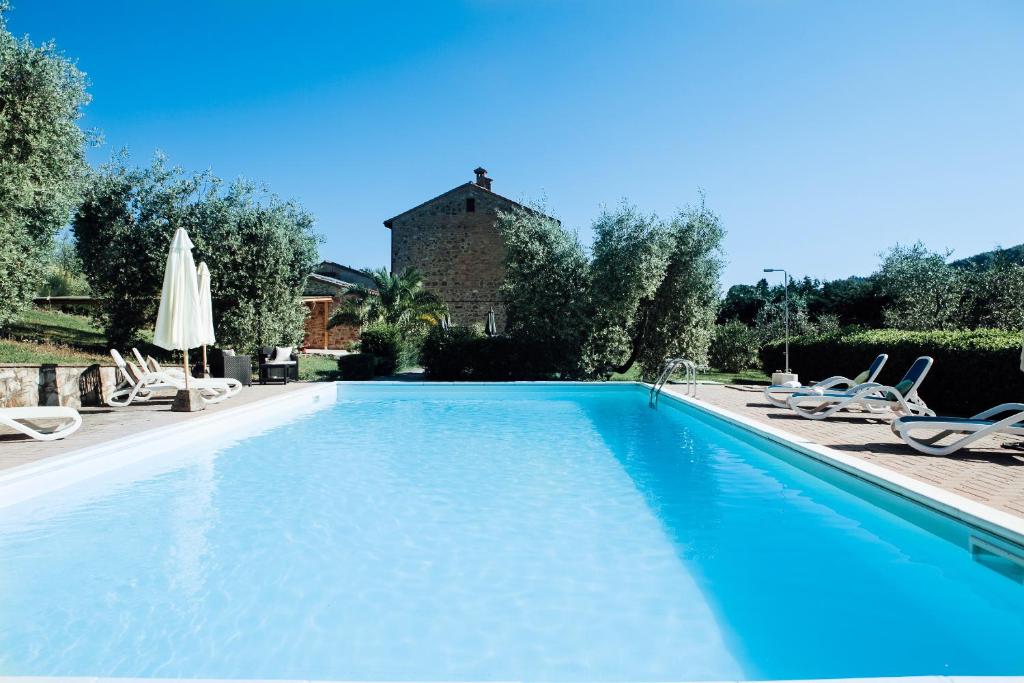 una piscina azul con sillas y un edificio en Il Vecchio Mulino Toscana, en Radicondoli