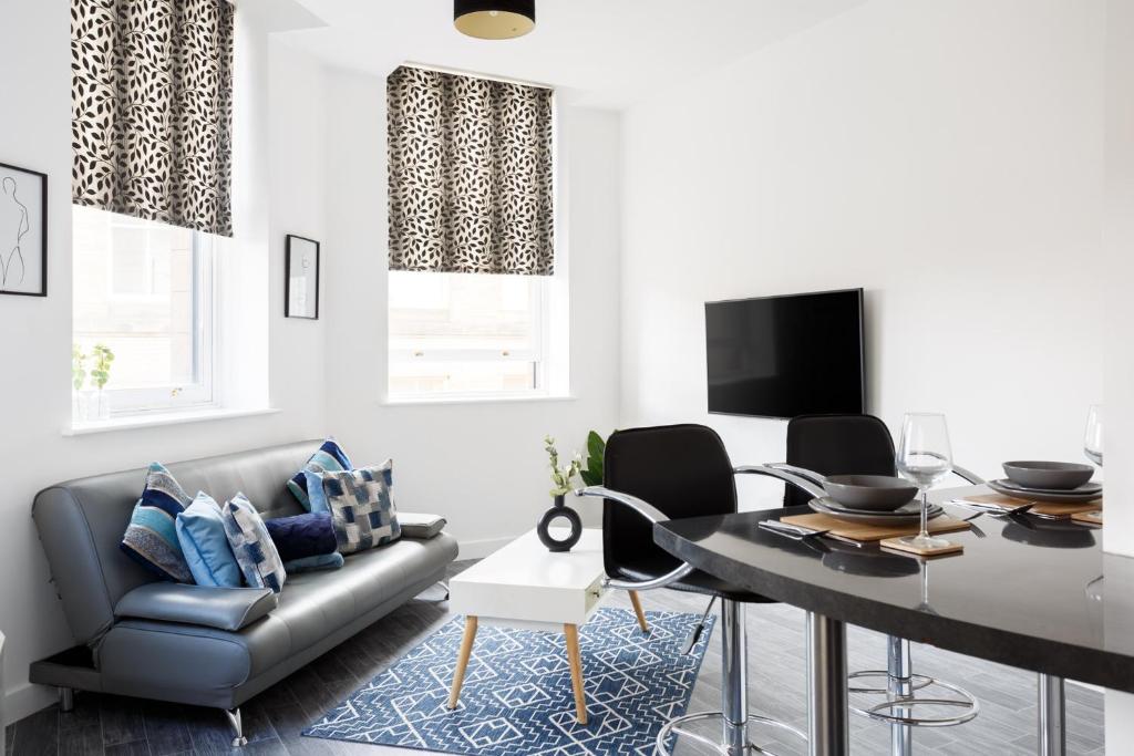 City-Centric Living Cozy 1-Bedroom Apartment في برادفورد: غرفة معيشة مع أريكة وطاولة طعام