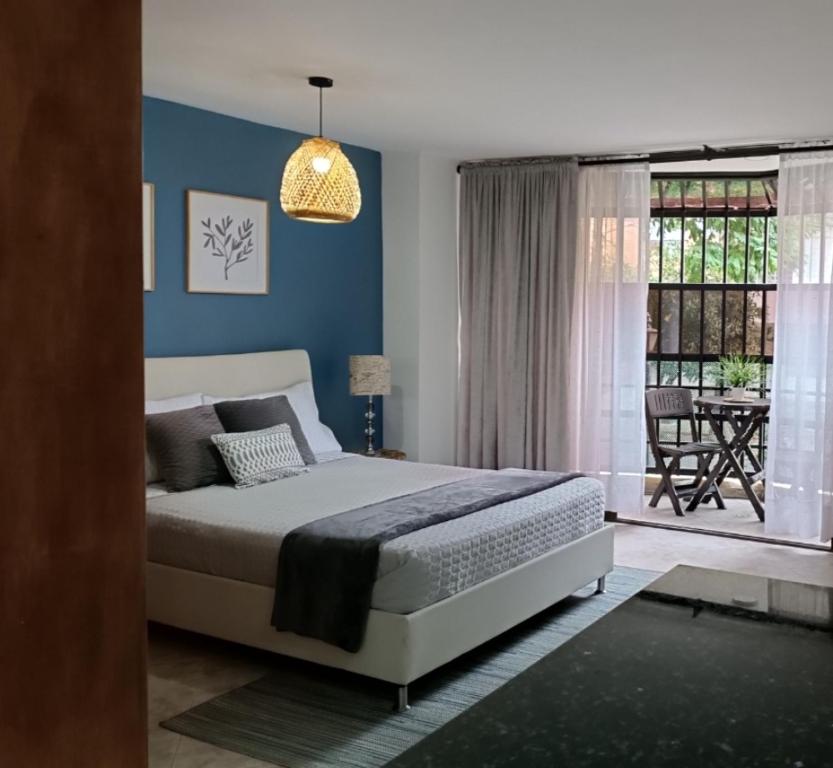 Un dormitorio con una cama con paredes azules y una ventana en Acogedor apartaestudio ubicado en Laureles, en Medellín