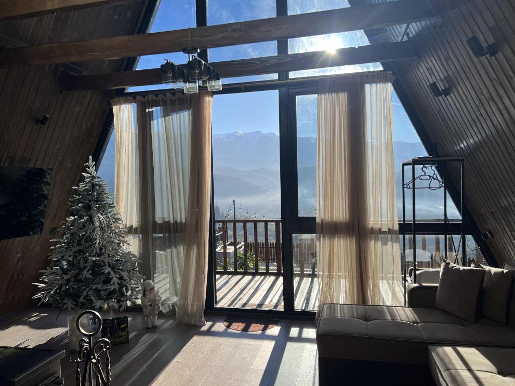 ein Wohnzimmer mit einem Weihnachtsbaum und einem großen Fenster in der Unterkunft UkhutiEcoHouse in Vani